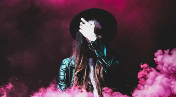 Woman in leather jacket surrounded by pink smoke