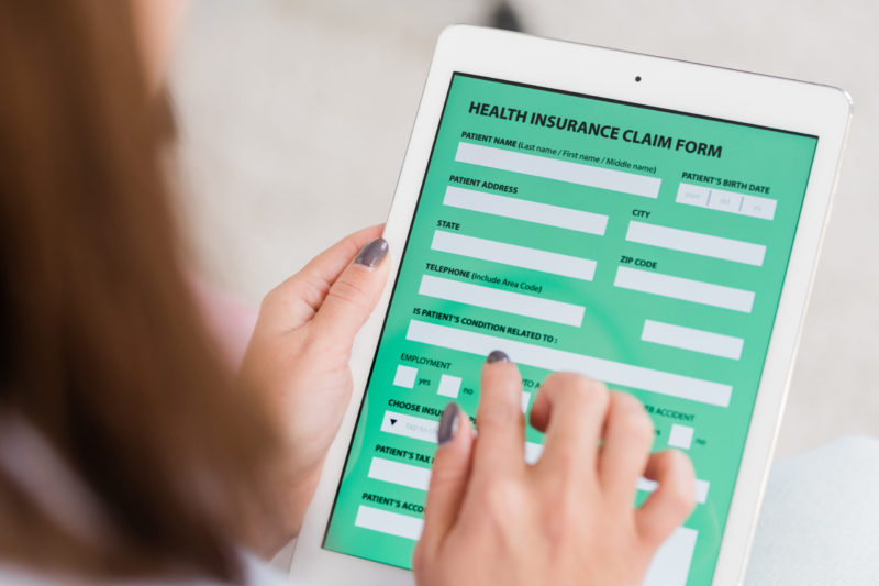 Woman filling out health insurance claim form on tablet